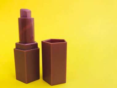 Sarı, parlak bir arka planda mat ruj. kalp şeklinde bej ruj, yumuşak kahverengi ton. Çıplak dudak makyajı. Güzel bir gölge, güzel bir açık renk makyaj..