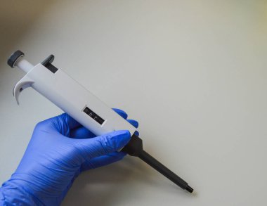 Biyokimya laboratuvarında çalışan sıhhiye yardımcısı koruyucu giysi giyen otomatik pipetle çalışıyor. Modern laboratuardaki kimyager covid-19 ile küresel salgın sırasında dağıtıcı kullanarak araştırma yapıyor..