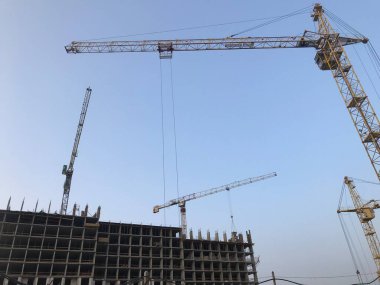 Beton bloklardan bir ev inşa etmek. Büyük, sarı bir vinç beton bloklarını bir yüksekliğe taşıyor. Çok katlı bir binanın inşaatı.