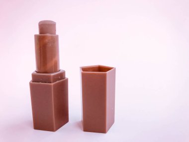 Pembe parlak bir arka planda mat ruj izi. kalp şeklinde bej ruj, yumuşak kahverengi ton. Çıplak dudak makyajı, kozmetik çanta için kompakt tüp..