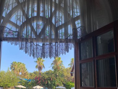 Palmiye ağaçları ve denizin üzerine penceresinden görüşlerini.