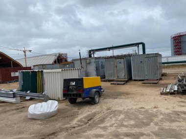 Gasoline portable electric generator, standby for emergency, in case of outage at construction site with garden background.