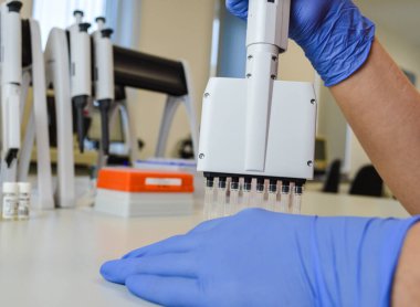 Kapat. Kadın bilim adamı bir laboratuvar şişesinde sıvı inceliyor..