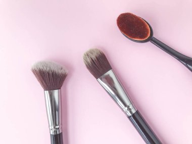 Fırçalar parlak bir arka planda yatar. Temeli, pudrayı ve allığı sürmek için doğal kılları olan kabarık fırçalar. cilt üzerindeki sıvı dokuyu harmanlamak için fırça.