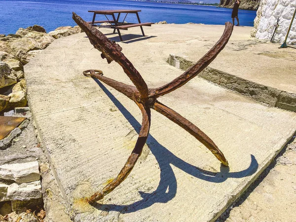 old, rusty anchor on the seashore. at the port with ships and yachts there is an anchor. tourists can see rust at anchor. marine stopper in rust, water rust.