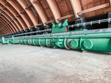 İnşaat malzemeleri olan ahşap bir depo. İnşaat için uygun birçok yapı bir depoda depolanmaktadır. Deponun içinde yeşil metal yapı - yüksek katlı vinç.