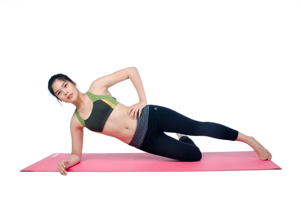 Hermosa mujer haciendo ejercicio en interiores usando alfombra de yoga rosa —  Fotos de Stock
