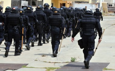 Polis memurları tam koruyucu giysiler içinde bir sivil huzursuzluk cevap verin.