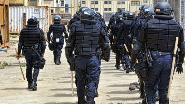 Polis memurları tam koruyucu giysiler içinde bir sivil huzursuzluk cevap verin.