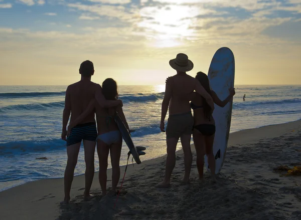 Dos parejas de surfistas en la playa al atardecer — Foto de Stock