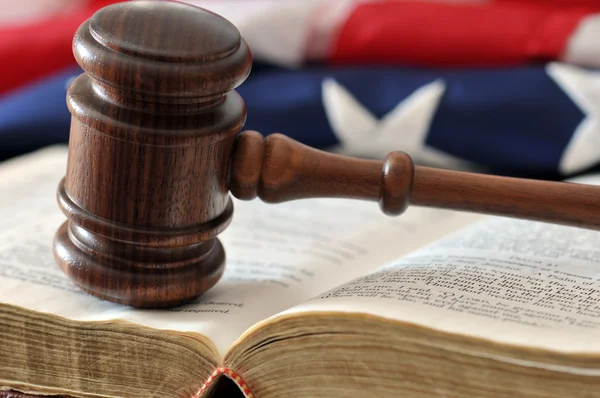 Gavel sobre livro resistido com bandeira no fundo — Fotografia de Stock