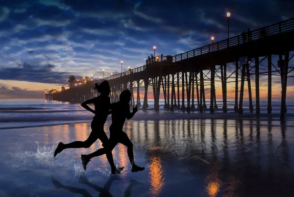 Surfer bewonderen zonsondergang in de buurt van oceanside pier — Stockfoto