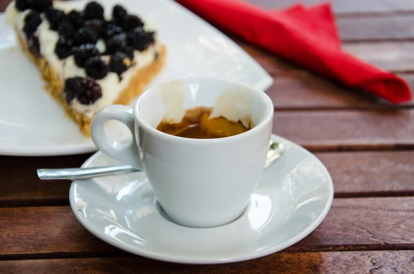 Weiße Espressotasse und ein Stück Brombeerkäsekuchen — Stockfoto