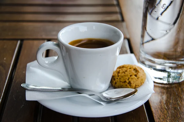 Tazza espresso bianca, biscotto e bicchiere di acqua fredda — Foto Stock