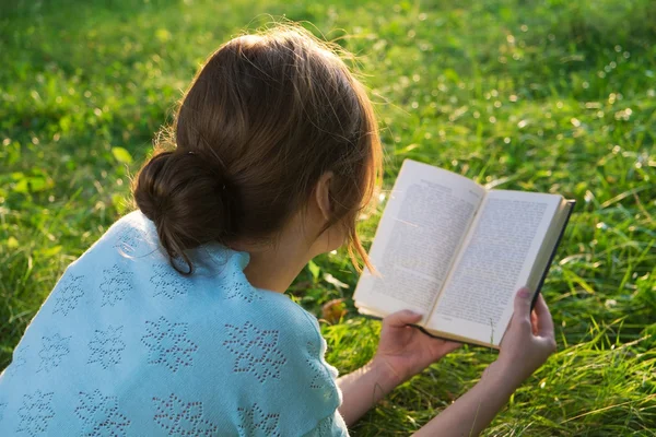 Junges schönes Mädchen liest ein Buch im Park — Stockfoto