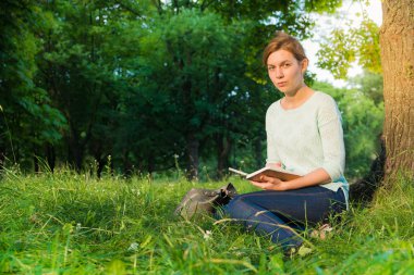 genç güzel kız parkta oturan ve bir defterde yazılı