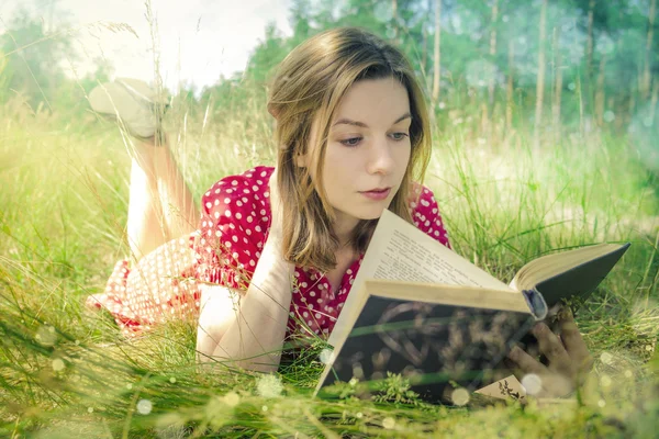 Junges schönes Mädchen liest ein Buch im Park — Stockfoto