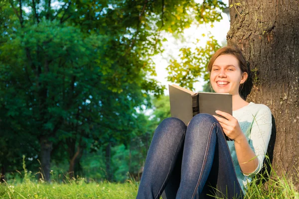 Junges schönes Mädchen liest ein Buch im Park — Stockfoto