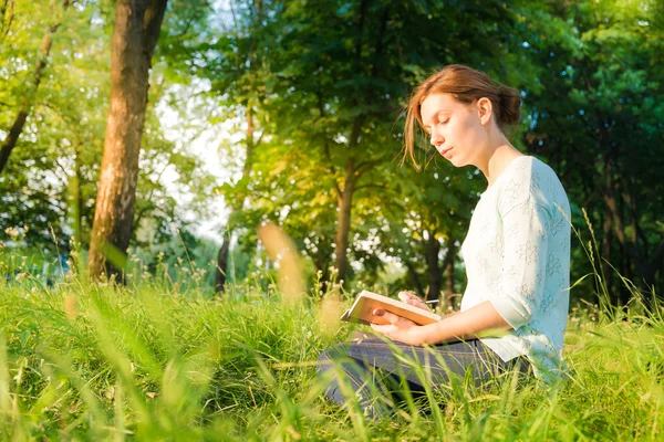 genç güzel kız parkta oturan ve bir defterde yazılı