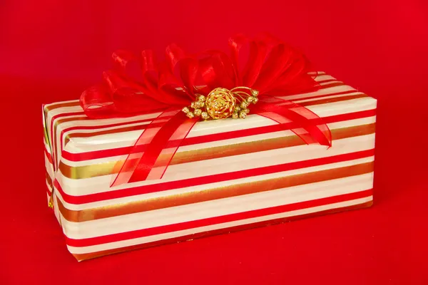 Rot, gold und weiß gestreiftes Geschenkpaket mit roten Bändern — Stockfoto