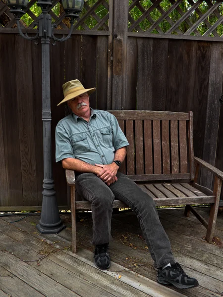 Man in een hoed dutten op een bankje — Stockfoto