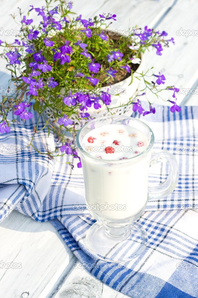 Milk with raspberries in cup and flowers