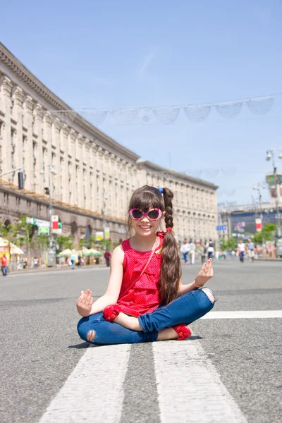 Smiling girl sits in lotus position on main street of Kiev, Ukraine — Stock Photo, Image