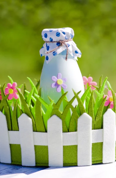 Bottle of milk in decorative basket with flowers — Stock Photo, Image