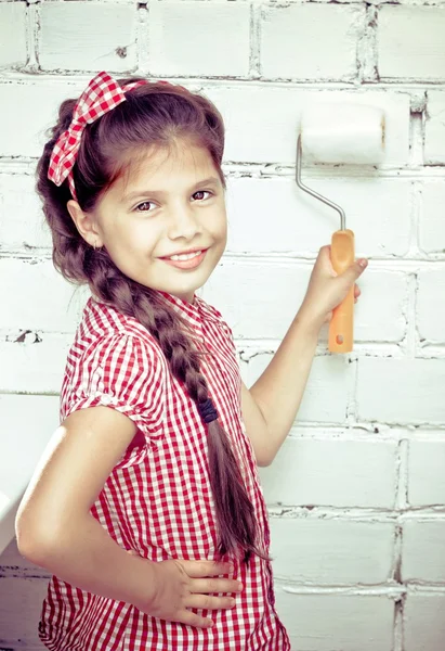 Girl holding paint roller on brick wall — Stock Photo, Image