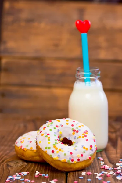 Doughnuts with mini bottle of milk and straw with heart. Focus on doughnuts — Stock Photo, Image