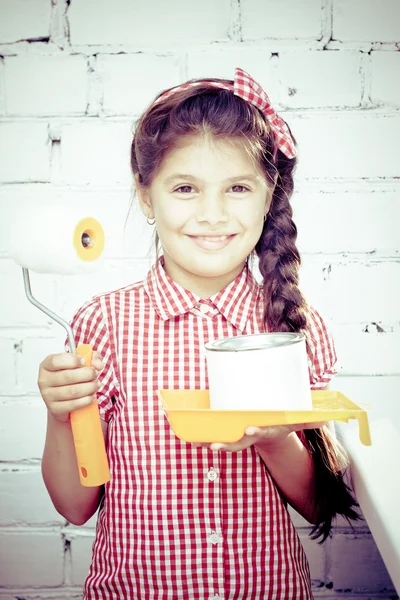 Girl holding paint roller on brick wall — Stock Photo, Image