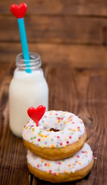 Doughnuts with mini bottle of milk and straw with heart. Focus on doughnuts — Stock Photo, Image