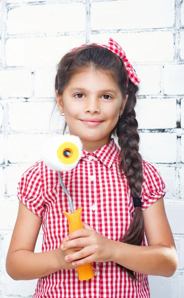 Girl holding paint roller on brick wall — Stock Photo, Image