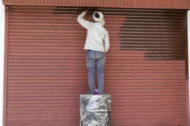 Asya, Hindistan eski bir garaj kapısı üzerinde çalışan ressam