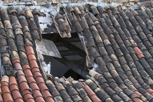 Velho telhado de azulejos com um grande buraco — Fotografia de Stock