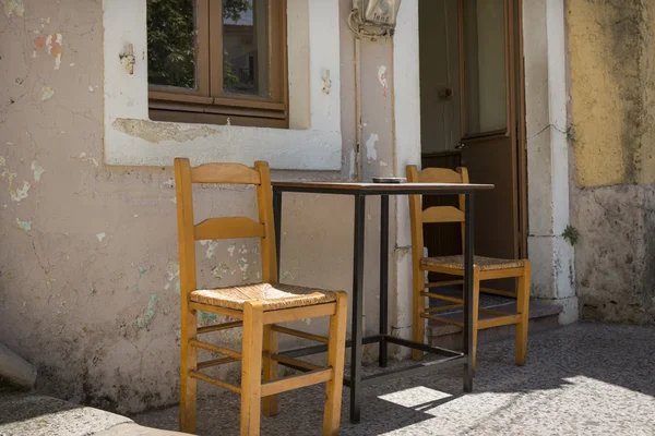 Mesa e cadeiras em frente a um restaurante na Grécia — Fotografia de Stock