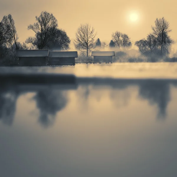 Boathouses pe un lac în timpul iernii cu ceață și soare — Fotografie, imagine de stoc