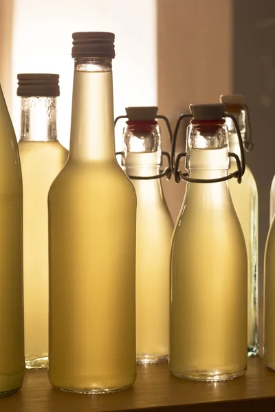 Bottles filled with elderflower syrup against the light — Stock Photo, Image