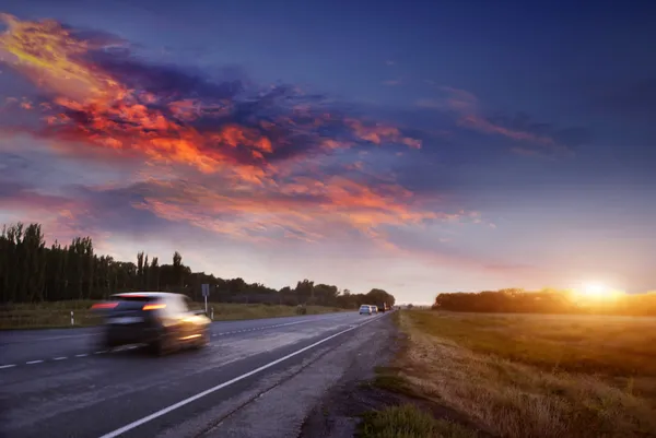 Voiture sur la route au coucher du soleil — Photo