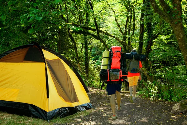 Tenda gialla e turisti con zaini — Foto Stock