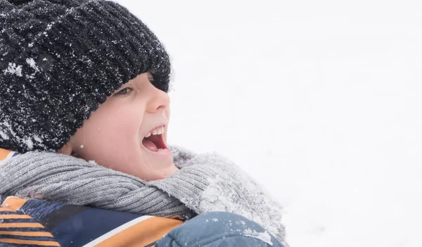 Ein Kleiner Junge Winter Mit Schneebedeckter Mütze Liegt Auf Dem lizenzfreie Stockbilder