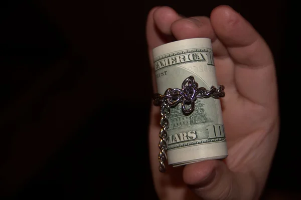 Hand is holding the roll of dollars on black background — Stock Photo, Image