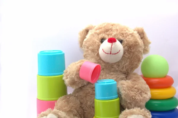 Teddy bear játszik a színes poharak — Stock Fotó