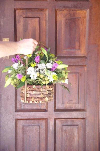 Flores em um cesto na mão do homem diante da porta — Fotografia de Stock