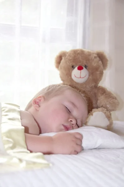 Un niño de un año se acuesta con un osito de peluche — Foto de Stock