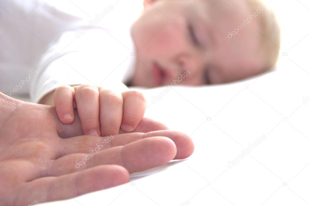 Sleeping boy is holding father's hand
