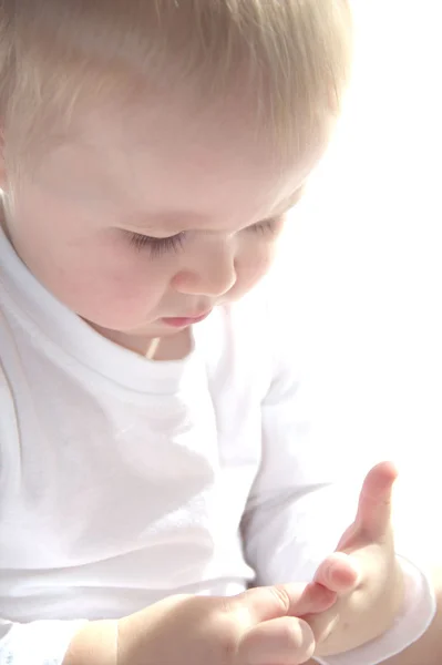 Little boy is looking at his hands on white background — Stock Photo, Image