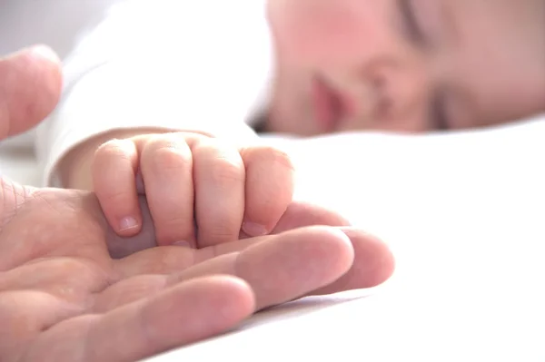 Dormir niño pequeño está sosteniendo la mano del padre —  Fotos de Stock