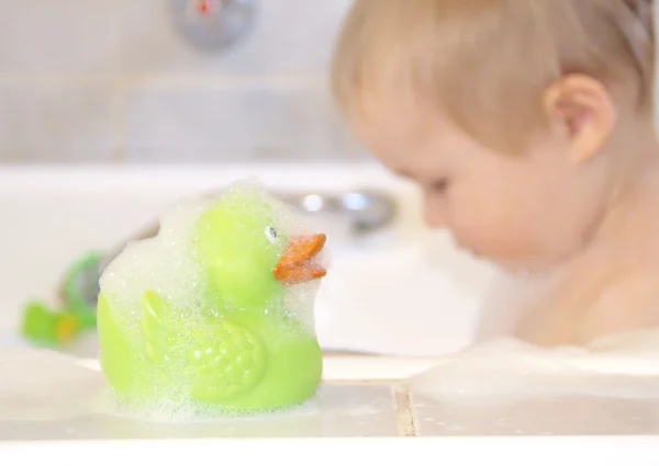 Green bath duck and bathing boy in the background — Stock Photo, Image