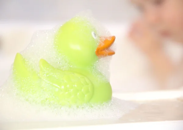 Bath duck and bathing child in the background — Stock Photo, Image